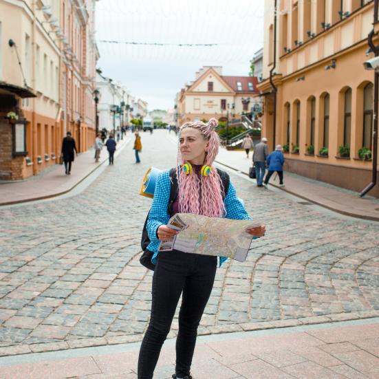 kvindelig ung turist står med et kort i en fremmed by