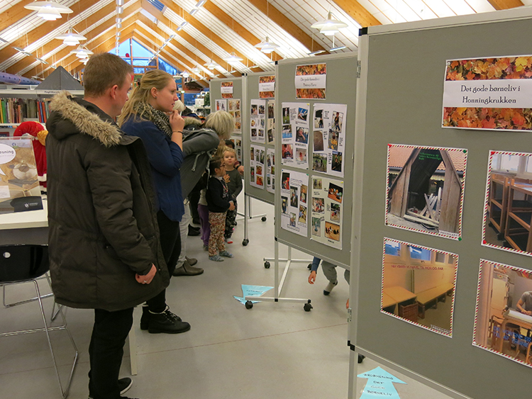  Børn og voksne kigger på udstilling i biblioteket 
