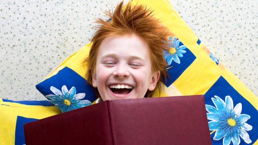 Foto: Dreng læser bog og griner